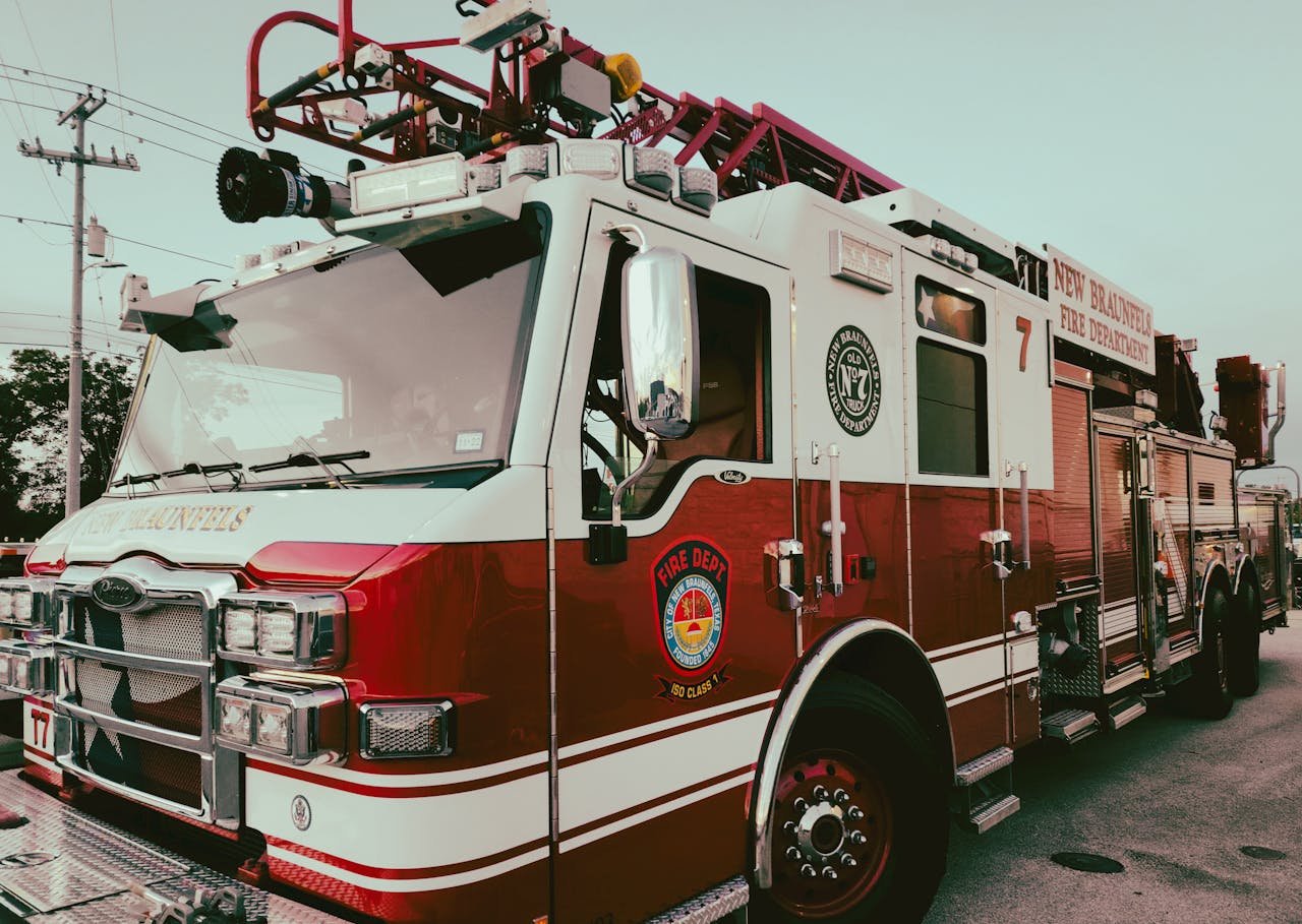 Red and white fire truck from New Braunfels Fire Department parked outdoors.